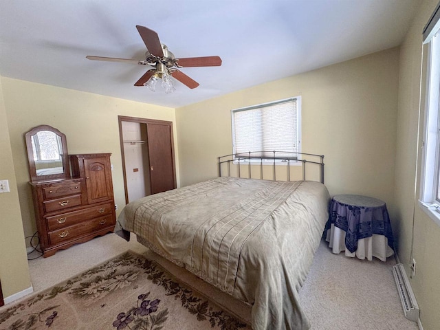 bedroom featuring a baseboard radiator, light carpet, a closet, and ceiling fan