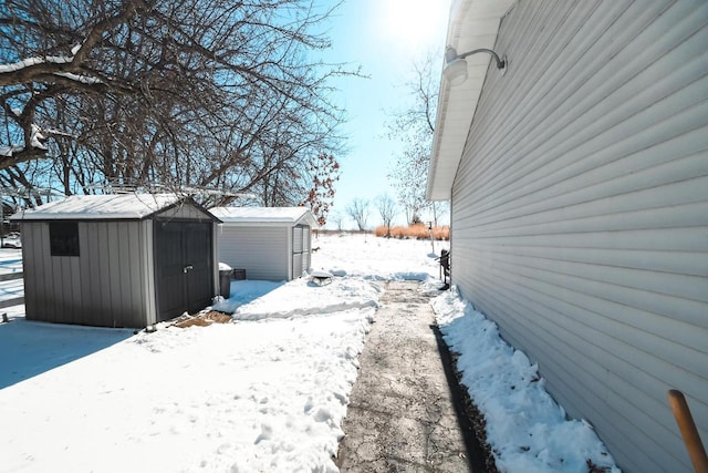 view of snowy exterior with an outbuilding and a shed