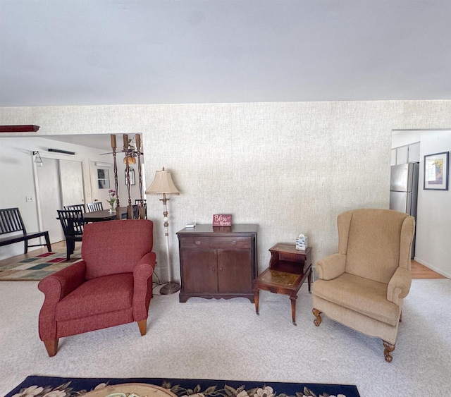 carpeted living area with wallpapered walls