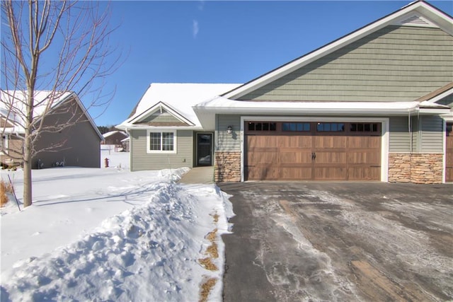 view of front of home with stone siding, an attached garage, and driveway