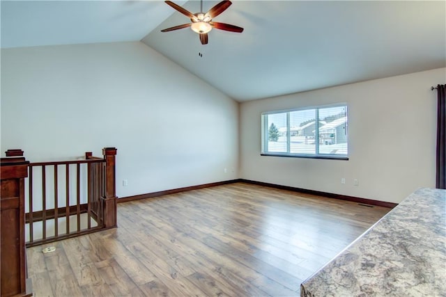 spare room with vaulted ceiling, wood finished floors, a ceiling fan, and baseboards