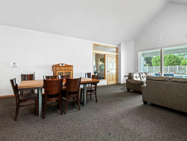 dining area with high vaulted ceiling and dark carpet