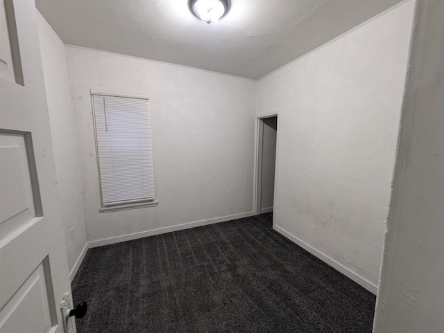 unfurnished room with dark colored carpet and baseboards