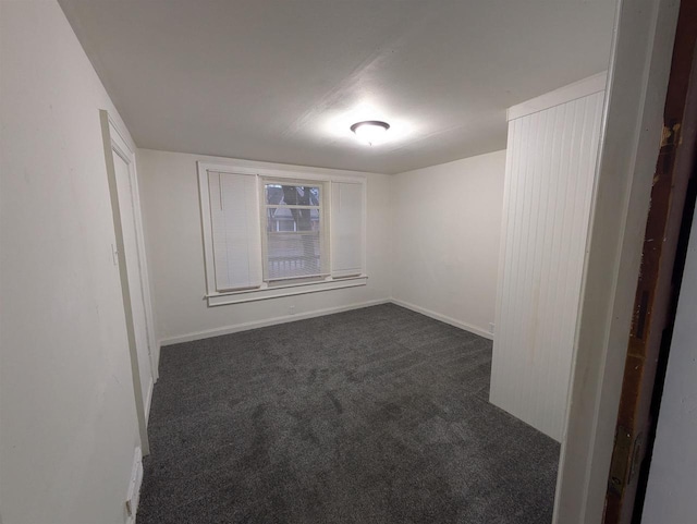 empty room with dark colored carpet and baseboards