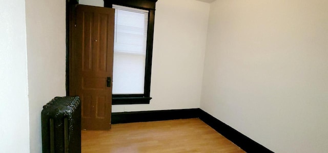 spare room featuring radiator heating unit, wood finished floors, and baseboards