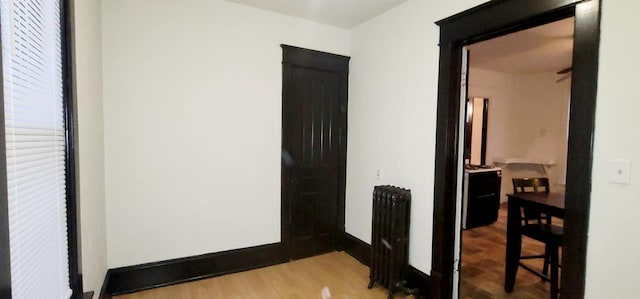 bedroom featuring baseboards, wood finished floors, and radiator