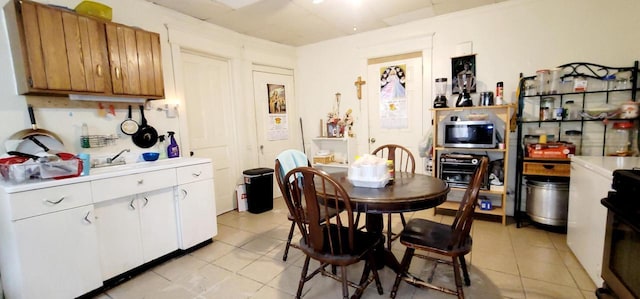 kitchen with brown cabinetry, white cabinetry, light countertops, and stainless steel microwave