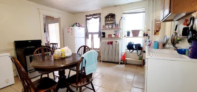 dining space with light tile patterned flooring and radiator heating unit