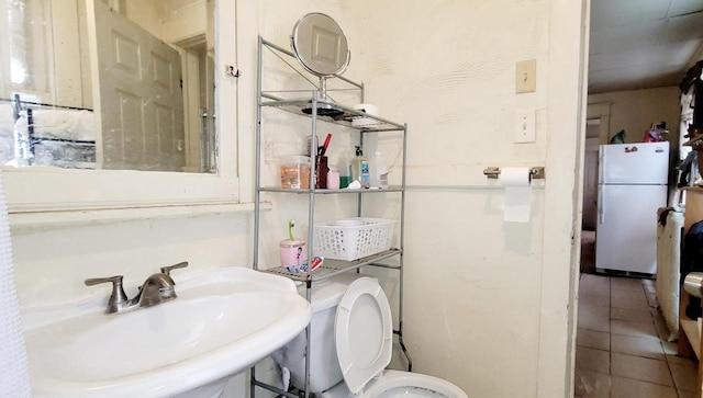 bathroom featuring toilet, tile patterned flooring, and a sink