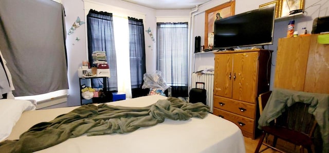 bedroom with radiator heating unit and multiple windows