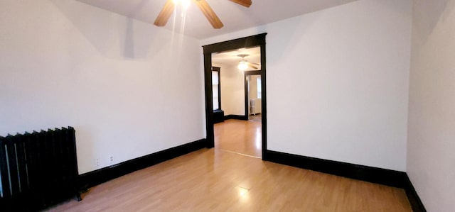 spare room with radiator, light wood-style floors, and baseboards