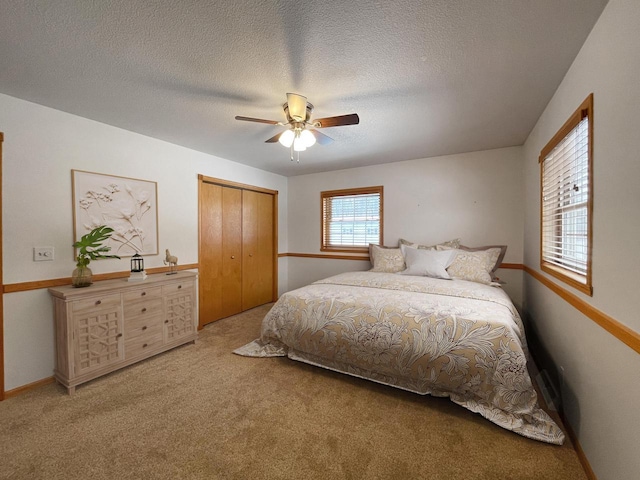 carpeted bedroom featuring baseboards, a textured ceiling, a ceiling fan, and a closet