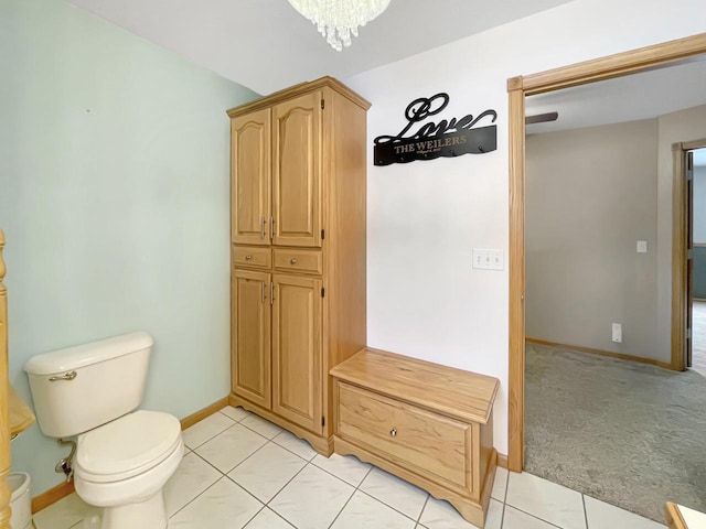 bathroom with a chandelier, tile patterned flooring, baseboards, and toilet