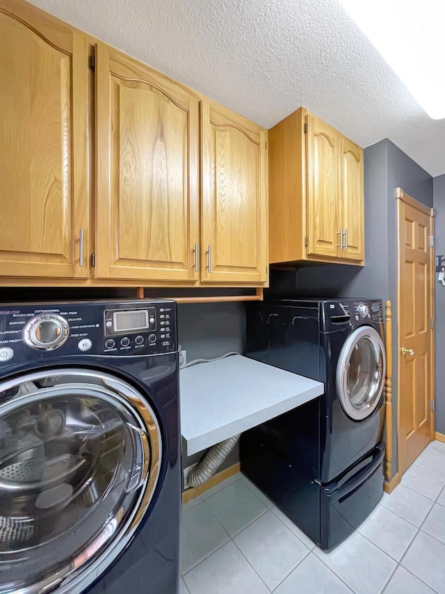 clothes washing area featuring cabinet space, light tile patterned floors, a textured ceiling, and independent washer and dryer