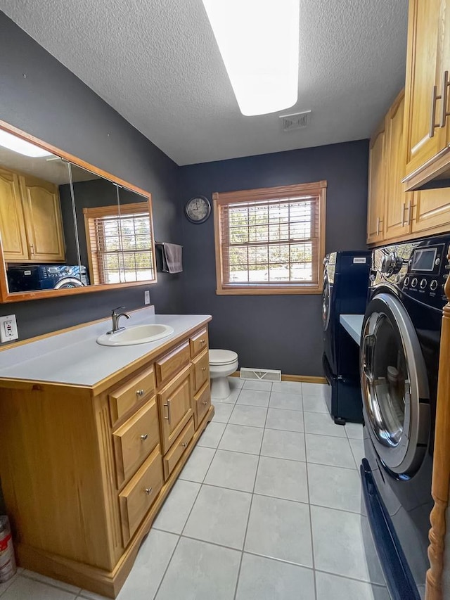 clothes washing area with washer / dryer, laundry area, visible vents, a sink, and light tile patterned flooring