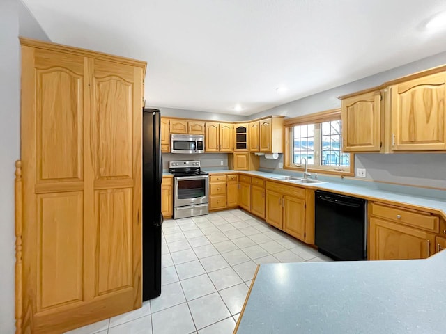 kitchen featuring light tile patterned floors, light countertops, light brown cabinetry, black appliances, and a sink