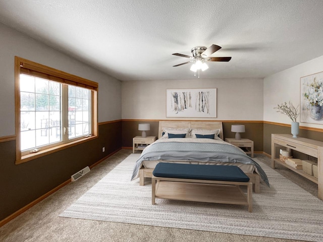 bedroom featuring baseboards, visible vents, ceiling fan, carpet, and a textured ceiling