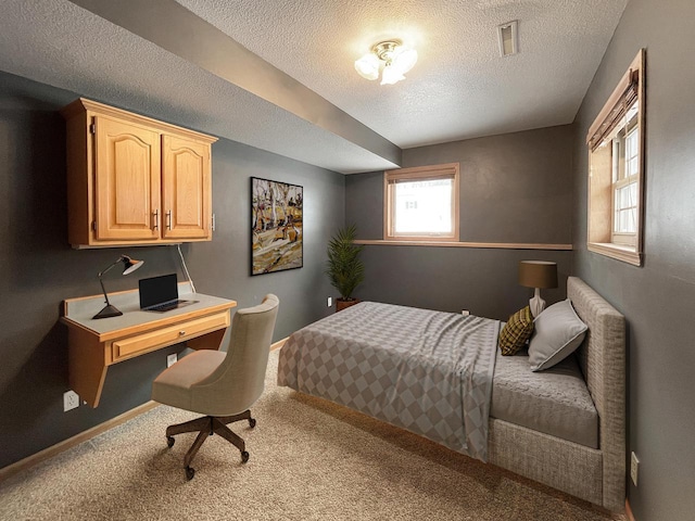 bedroom with carpet, visible vents, and a textured ceiling