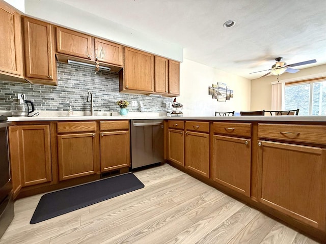 kitchen with a sink, brown cabinets, light countertops, and stainless steel dishwasher