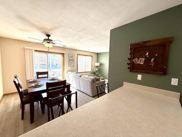 dining room with a textured ceiling, wood finished floors, a ceiling fan, and baseboards