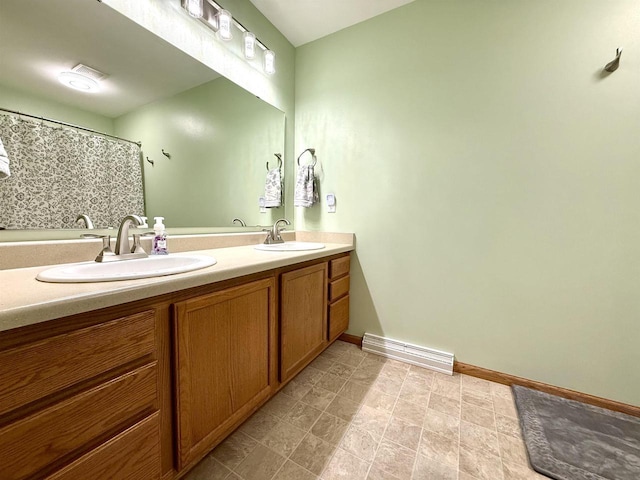 bathroom with double vanity, baseboards, and a sink