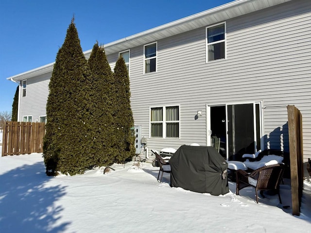 snow covered rear of property with fence