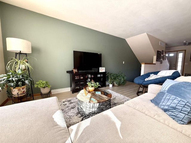 living room featuring lofted ceiling, baseboards, visible vents, and wood finished floors