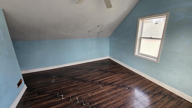 additional living space featuring dark wood-style floors, lofted ceiling, a ceiling fan, and baseboards