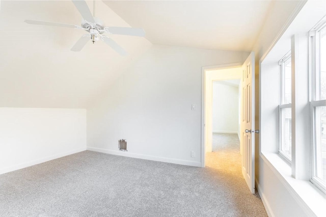 unfurnished room featuring a wealth of natural light, lofted ceiling, carpet flooring, and baseboards