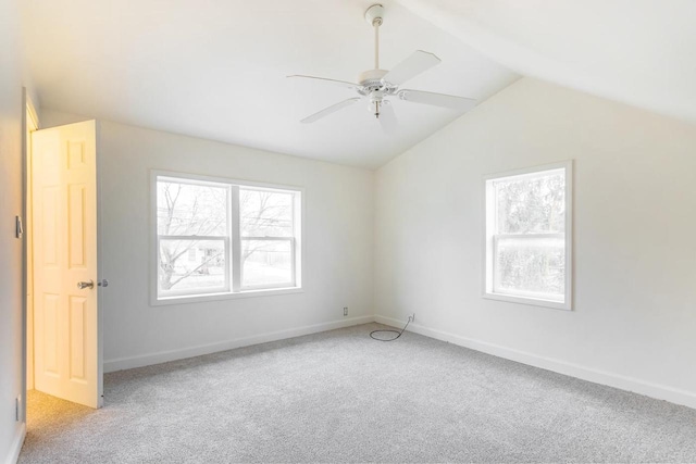 spare room featuring light colored carpet, vaulted ceiling, baseboards, and ceiling fan