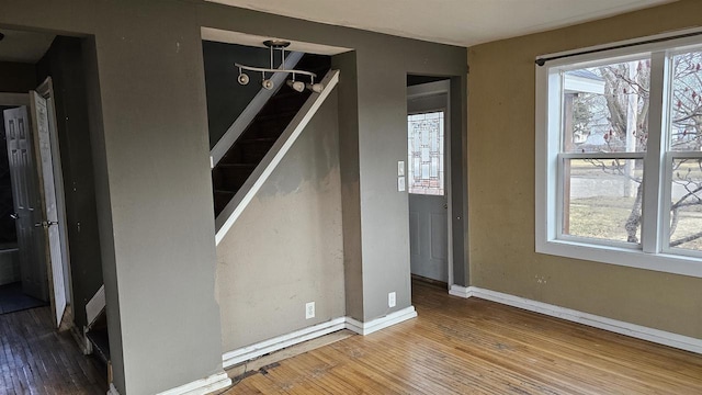 interior space with baseboards, hardwood / wood-style floors, and stairs