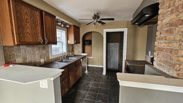 kitchen featuring arched walkways, range hood, decorative backsplash, a sink, and dishwasher