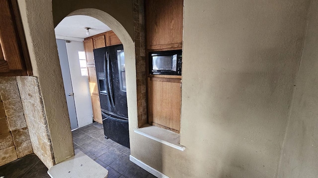 kitchen with arched walkways, black appliances, and brown cabinets