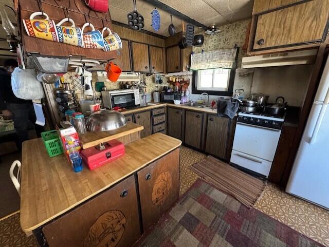 E7478 Hinkst Hollow Rd, Viroqua, WI 54665 - kitchen featuring dark floors, light countertops, a sink, white appliances, and under cabinet range hood