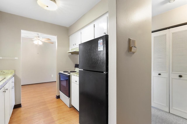 kitchen with light countertops, freestanding refrigerator, white cabinets, and white electric range