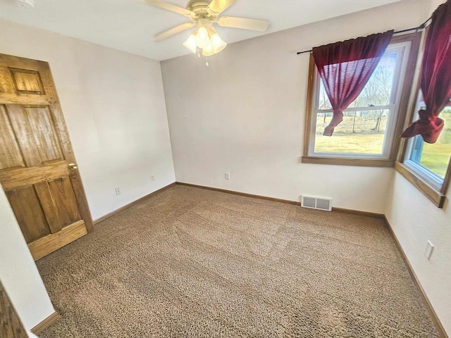 carpeted spare room with visible vents, baseboards, and a ceiling fan