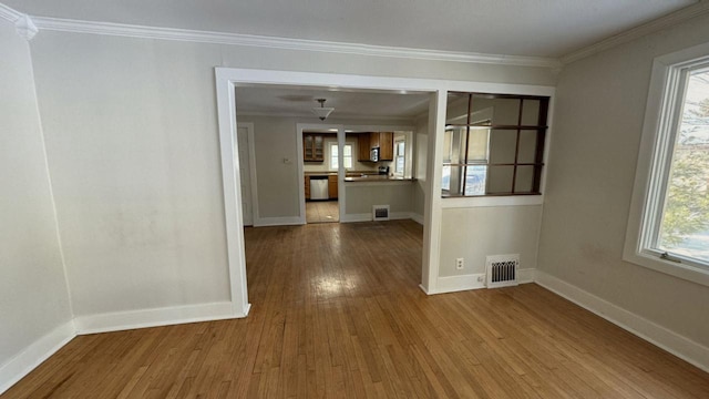 unfurnished dining area featuring baseboards, light wood finished floors, visible vents, and crown molding