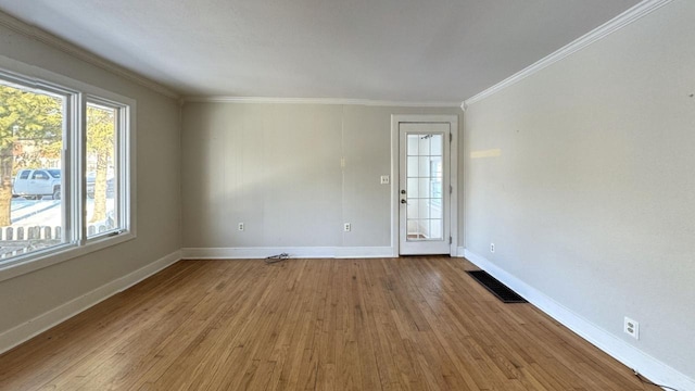 spare room featuring baseboards, visible vents, crown molding, and wood finished floors