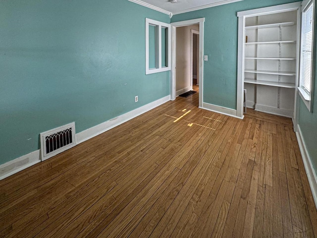 unfurnished bedroom with ornamental molding, wood finished floors, visible vents, and baseboards