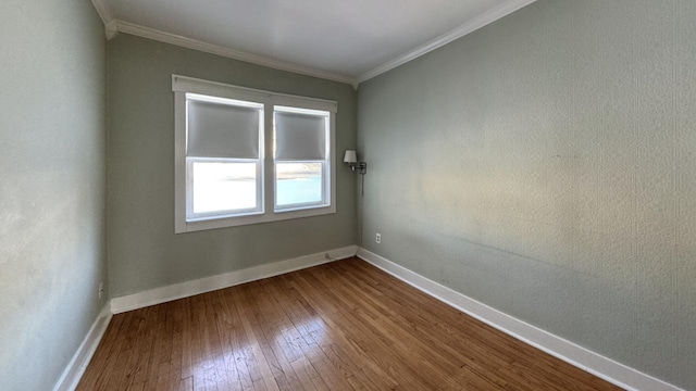 empty room featuring ornamental molding, wood finished floors, and baseboards