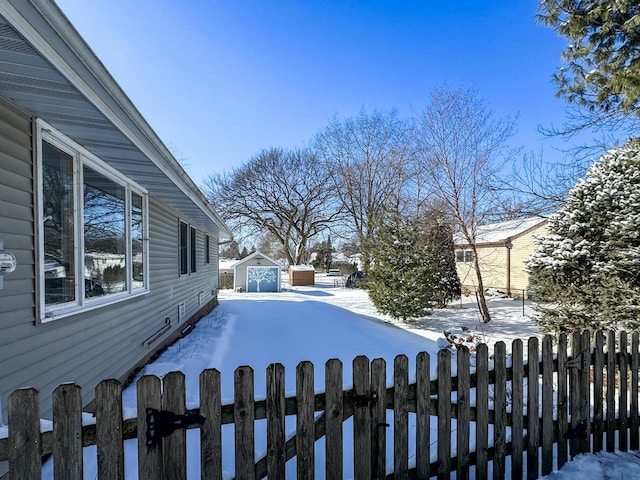 yard covered in snow with an outbuilding, fence, and a storage unit