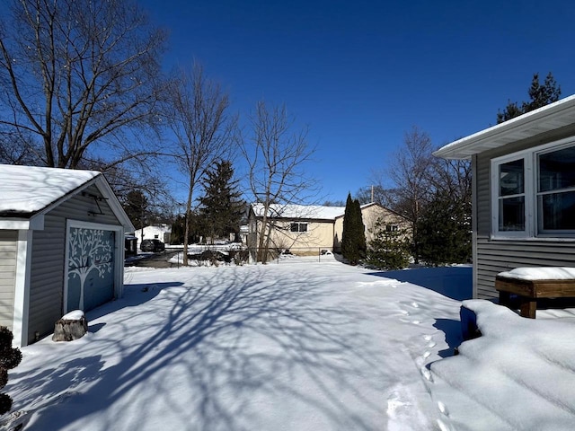 yard covered in snow featuring a detached garage