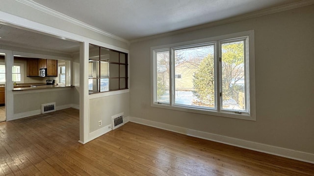 unfurnished dining area featuring baseboards, visible vents, crown molding, and wood finished floors