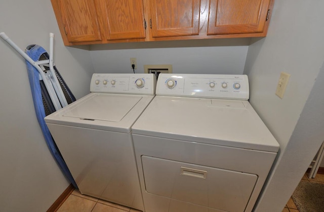 clothes washing area featuring light tile patterned flooring, cabinet space, and washer and dryer