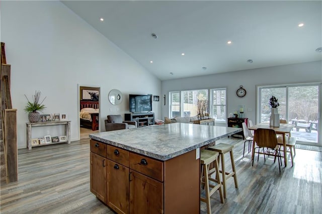 kitchen featuring light wood-style floors, open floor plan, light countertops, a center island, and brown cabinetry