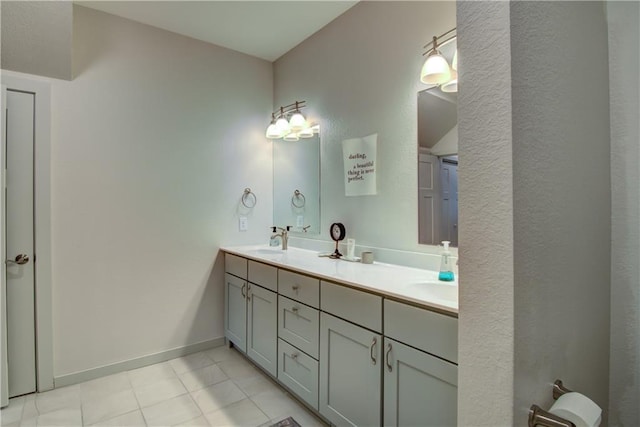 full bathroom with double vanity, tile patterned flooring, a sink, and baseboards