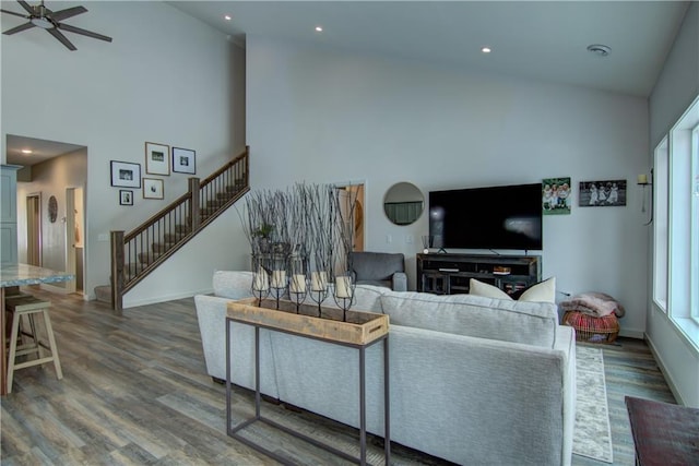 living room featuring high vaulted ceiling, wood finished floors, ceiling fan, and stairs