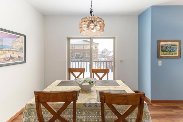 dining space with baseboards, light wood finished floors, and an inviting chandelier