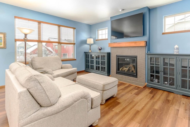 living room featuring a fireplace, plenty of natural light, baseboards, and wood finished floors