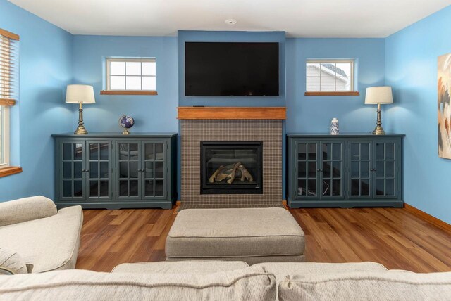 living area featuring baseboards, wood finished floors, and a tile fireplace